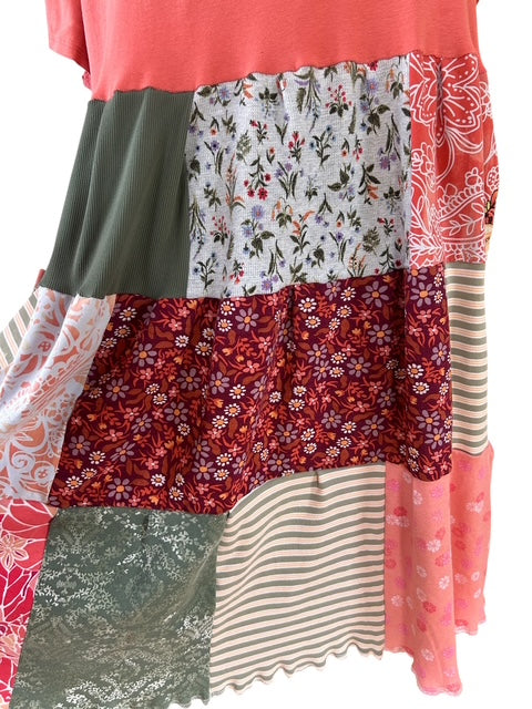 Close up of patchwork design with gray floral, green solid, peach floral, tan strip, pink floral, green greenery